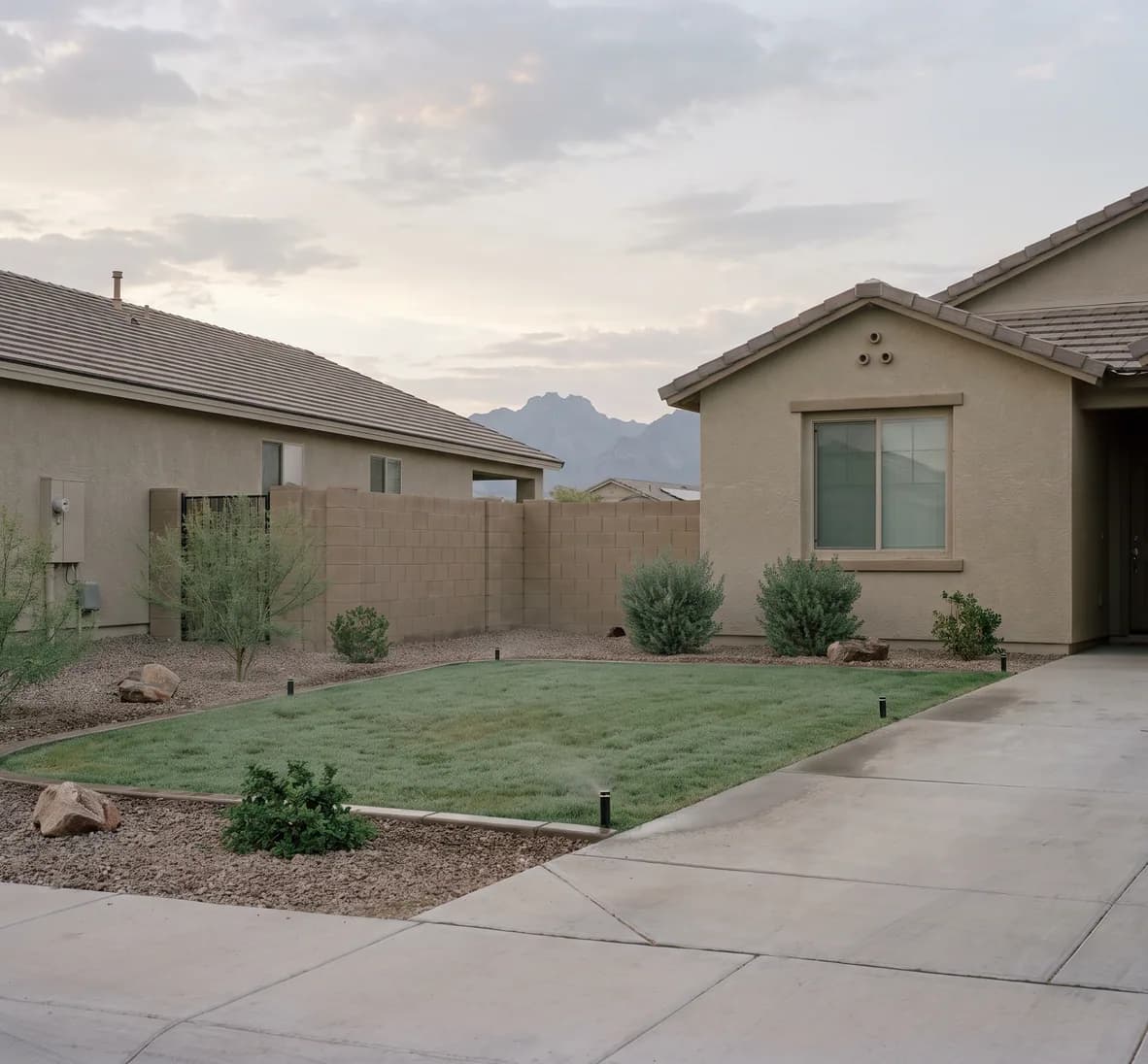 Matching spray heads reaching head to head on a small lawn, with the driveway and sidewalk left dry